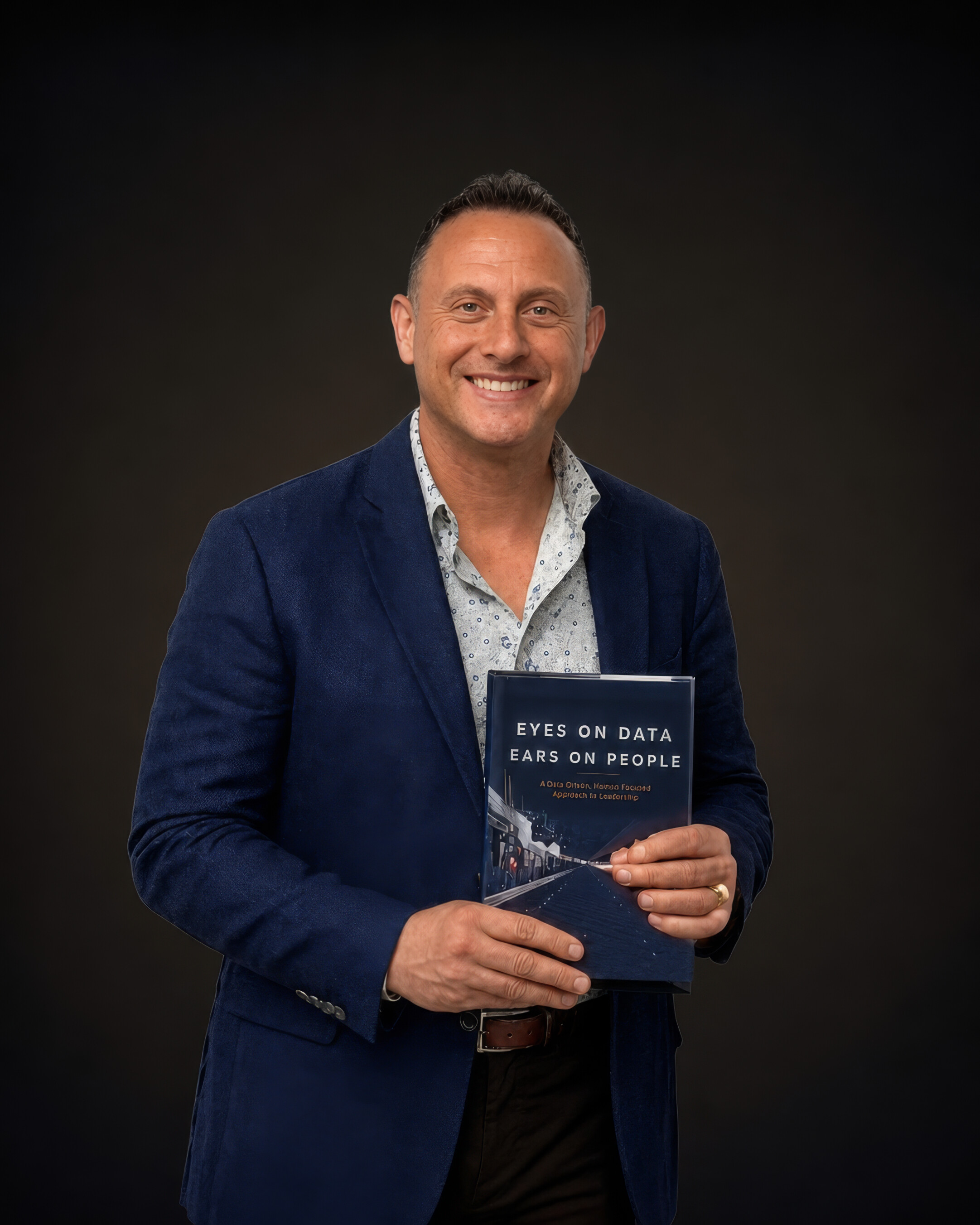 Dave Saben holding his book Eyes on Data, Ears on People